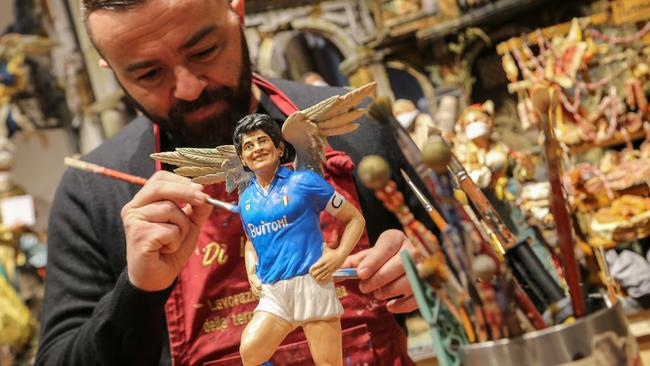 Gennaro Di Virgilio paints a statuette of Argentinian football legend Diego Maradona in San Gregorio Armeno. Picture: AFP