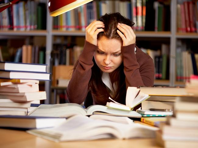 Portrait of troubled girl touching head while preparing for seminar in college library stressed high school kids . Picture: istock