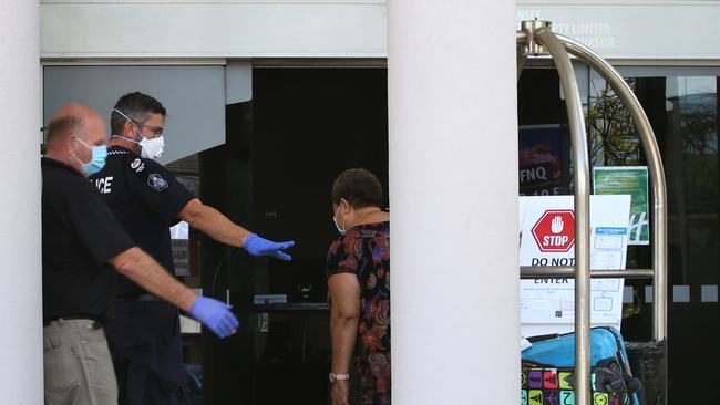 A police officer assists a guest arriving from Port Moresby about to undergo mandatory isolation at the Holiday Inn Cairns Harbourside. Picture: Peter Carruthers