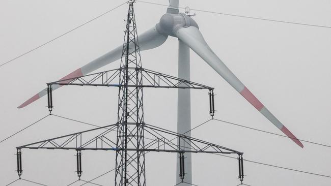 Wind turbines rotate behind a mast of a high-voltage electricity line near Uphusen, northern Germany, March 30, 2024. In the northern German lowlands, a large part of the renewable energy is generated by wind power. (Photo by FOCKE STRANGMANN / AFP)