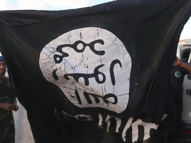 Iraqi security forces and allied Shiite militiamen celebrate as they hold a flag of the Islamic State group they captured in Tikrit, 80 miles (130 kilometers) north of Baghdad, Iraq, Tuesday, March 31, 2015. Iraqi forces battled Islamic State militants holed up in downtown Tikrit, going house to house Tuesday in search of snipers and booby traps, and the prime minister said security forces had reached the heart of the city. (AP Photo/Khalid Mohammed)