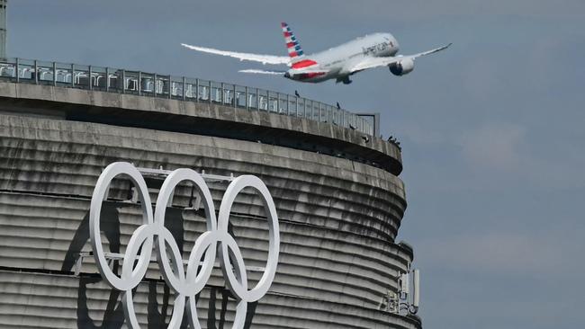 This photograph taken in Roissy-en-France on April 23, 2024, shows the Olympic rings on the Roissy - Charles de Gaulle Airport terminal 1, as an aircraft takes off. The Paris 2024 Olympics will take place from July 26 to August 11, 2024. (Photo by Miguel MEDINA / AFP)