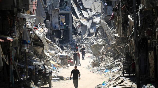 Palestinian men walk along a narrow street past destroyed buildings in Khan Yunis, in the southern Gaza Strip. Picture: AFP