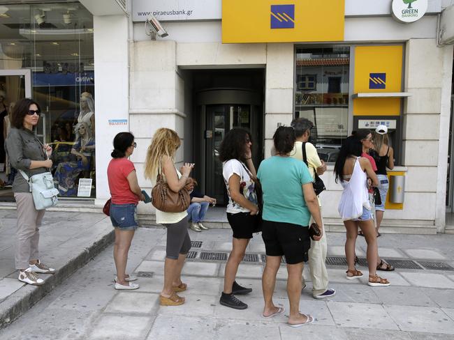 Queues continue ... people line up at an ATM outside a Piraeus bank branch in Athens. Picture: AP