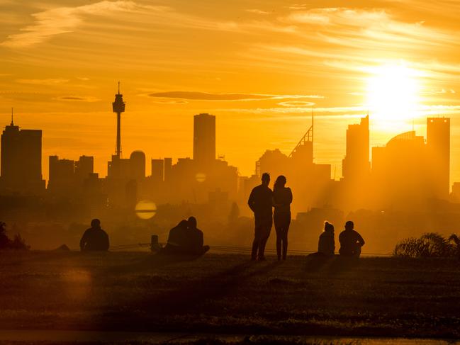 People watch as the Sun sets over the Sydney CBD after a hot spring day, Pictured from Dudley Page Reserve in Dover Heights,15th September 2019.Photo by Damian Shaw