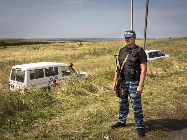 A member of a local militia stands guard as vehicles transporting observers from the Organisation for Security and Co-operation in Europe and International Committee of the Red Cross visit the main crash site of Malaysia Airlines flight MH17 in Grabovo, Ukraine. Picture: Rob Stothard/Getty Images