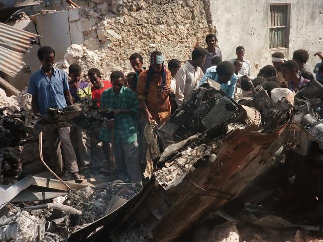 Somalis look at the wreckage of a US helicopter, in a Mogadishu street, 04 October 1993, after it was shot down. Twelve soldiers were killed, 76 wounded and six others reported missing, during a battle with followers of warlord Mohamed Farah Aidid, 03 October 1993. / AFP PHOTO / STR