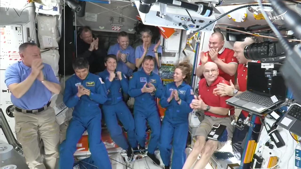 This image taken from a NASA livestream shows the SpaceX Dragon Crew-10 members (in dark blue) clapping after entering the International Space Station. Picture: NASA/AFP