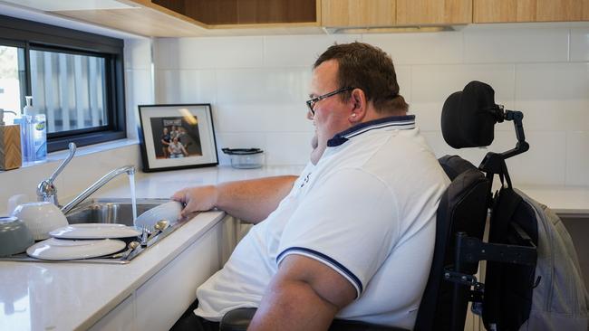 Logan man Brendon Woolf does the washing up in his new home at Loganlea.