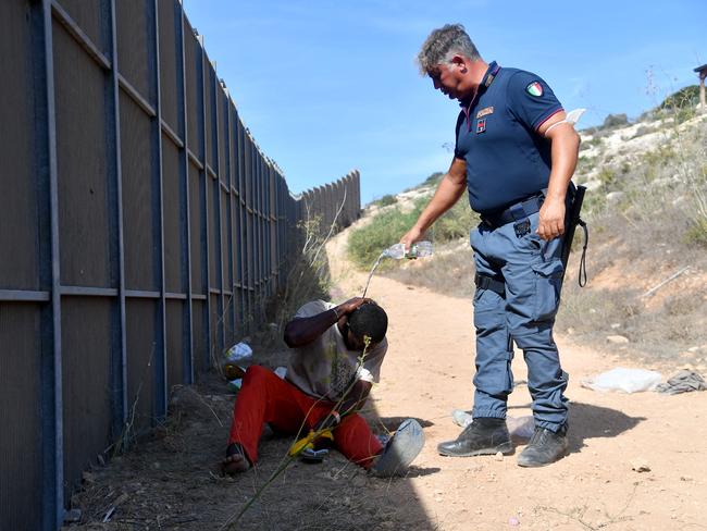 An Italian police officer sprays a migrant with fresh water after he has crossed the fence to exit the operational center called ‘Hotspot’ on the Italian island of Lampedusa. The number of migrants arriving in Italy after crossing on boats from North Africa has surged this year, at almost 124,000 since January - up from 65,500 during the same period in 2022. The Italian Red Cross, which has run the hotspot since June, said more than 100 landings within a few hours left it hosting more than 6,000 people in a facility built for fewer than 400. Picture: Alessandro Serrano/AFP 