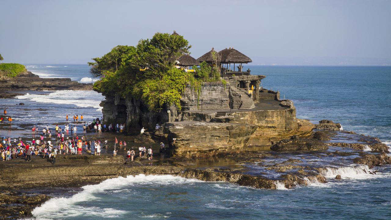 Tourists will now be banned from taking photos on rocky locations around Bali’s iconic Tanah Lot Temple when waves are rough. Picture: Getty