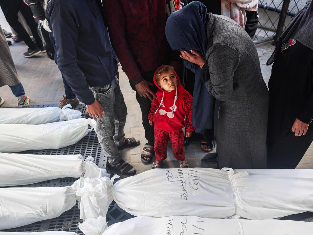 A child watches as a mourner cries over the bodies of the Nofal family, after they were killed during Israeli bombardment in the Gaza Strip. Picture: AFP