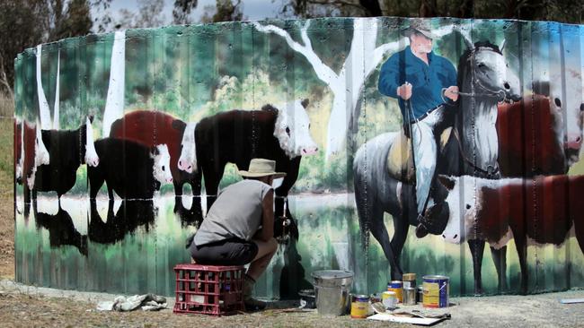 Omeo artist Terry Petersen works on a mural near the Ensay saleyards. Picture: Jason Palmer