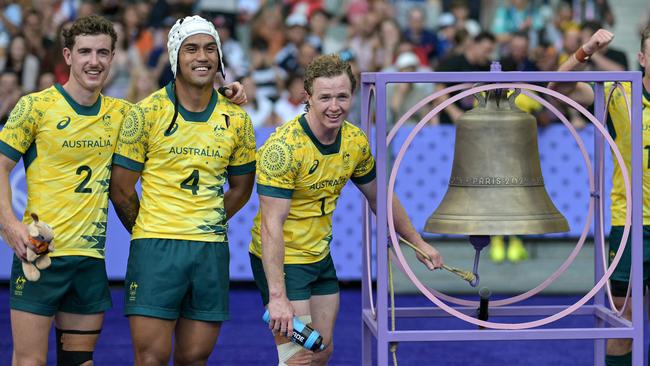 Australian players ring the bell after winning the men's pool B rugby sevens match between Australia and Kenya. Photo by CARL DE SOUZA / AFP.