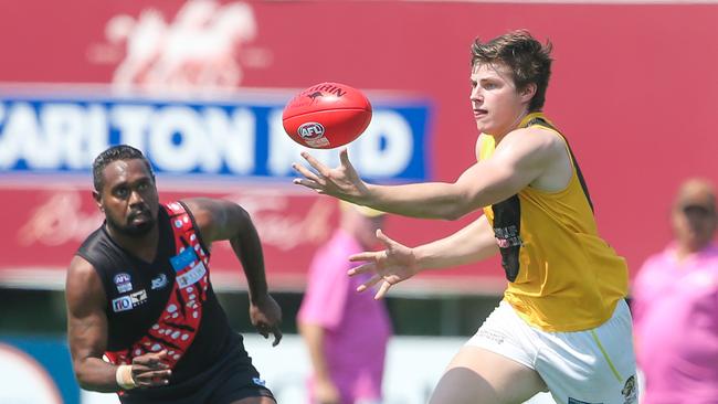 Nightcliff’s Matthew Bricknell has the ball on a string as Tiwi Bomber Paddy Heenan looms large. Picture: GLENN CAMPBELL