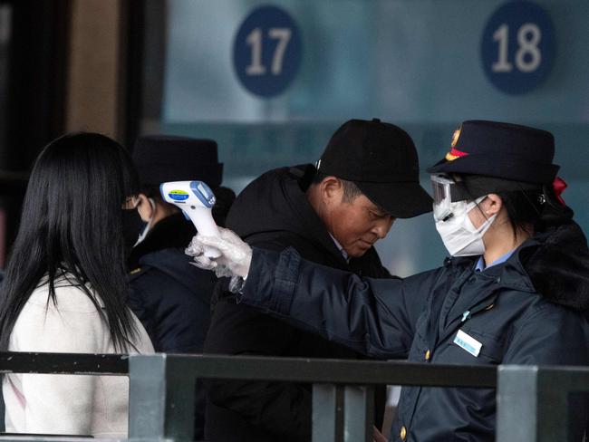 Security personnel checking the temperature of a passenger wearing a face mask at Beijing Railway Station in Beijing. Picture: AFP