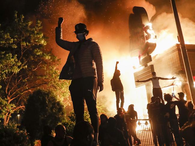 Protestors demonstrate outside of a burning fast food restaurant, early Friday, May 29, 2020, in Minneapolis. Protests over the death of George Floyd, a black man who died in police custody Monday, broke out in Minneapolis for a third straight night. (AP Photo/John Minchillo)