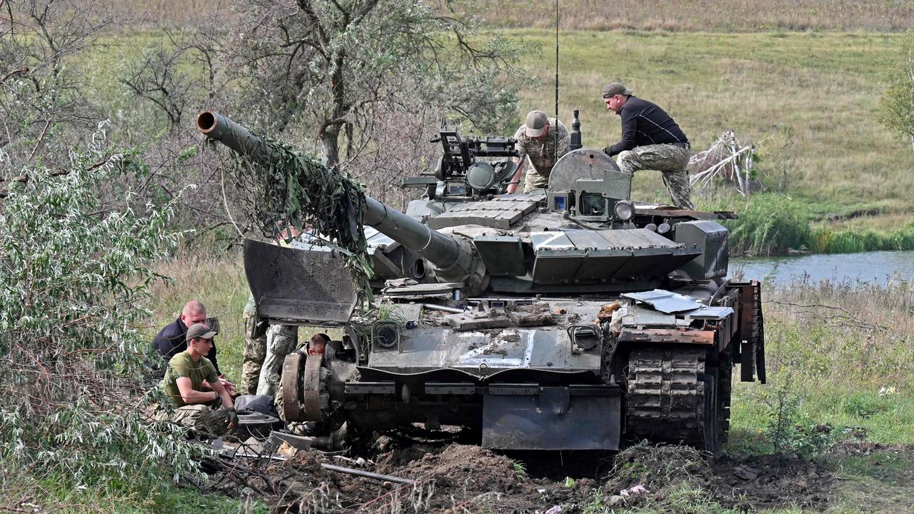 Ukrainian servicemen work on a tank abandoned by Russian troops during their retreat in the north of the Kharkiv region. Picture: Sergey Bobok/AFP