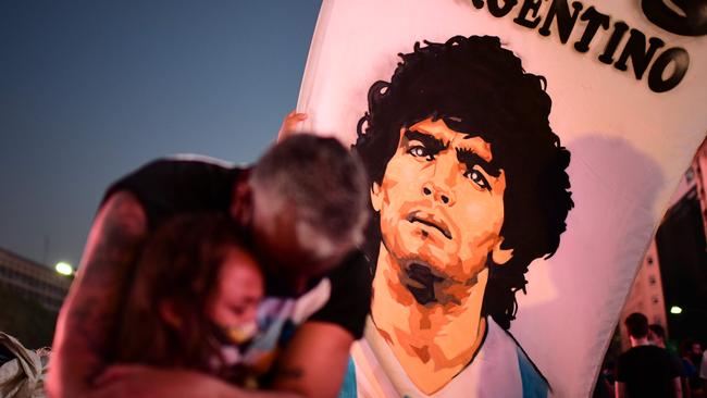 A father and her daughter, fans of Argentinian football legend Diego Maradona, mourn as they gather by the Obelisk to pay homage in Buenos Aires Picture: AFP