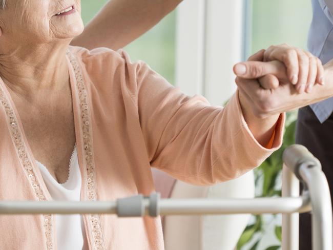 Old woman gets help with walking from a nurse