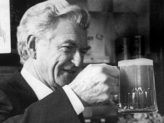 Then Prime Minister Bob Hawke admires a pint of ale he pulled himself from one of the traditional pumps at the Dog House pub at Frilford, near Oxford, where he famously once drank a yard glass in record time. Picture: AP