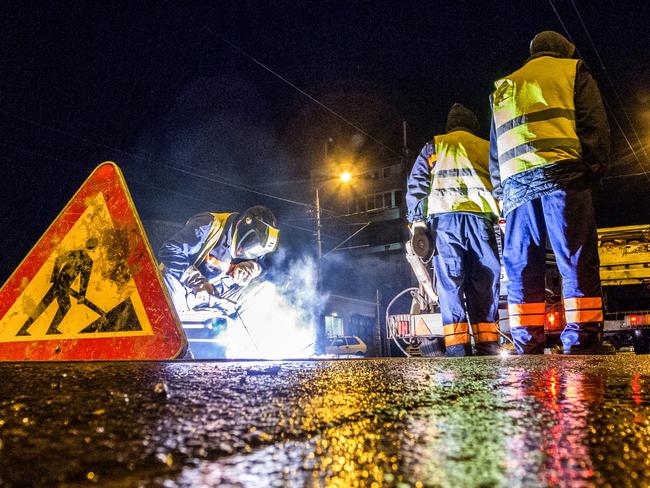 Low angle view of street workers and a welder while repairing the rail tracks in the city at night. Road sign is in front and truck with equipment is in the background. Picture: EXTREME-PHOTOGRAPHER/iStock