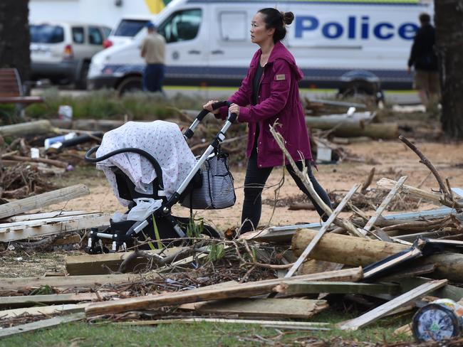 A mother navigates her way through debris at Collaroy. Picture: AAP