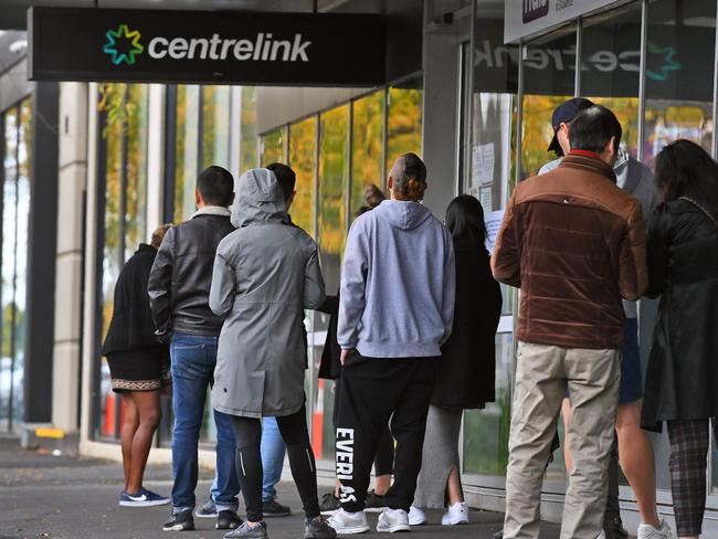 People queue up outside a Centrelink office in Melbourne on April 20, 2020, which delivers a range of government payments and services for retirees, the unemployed, families, carers and parents amongst others. - A report from the Grattan Institute predicts between 14 and 26 per cent of Australian workers could be out of work as a direct result of the coronavirus shutdown, and the crisis will have an enduring impact on jobs and the economy for years to come. (Photo by William WEST / AFP)