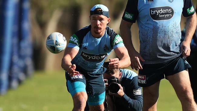 Damien Cook passes wet balls from a tub of water at training. Picture: Brett Costello