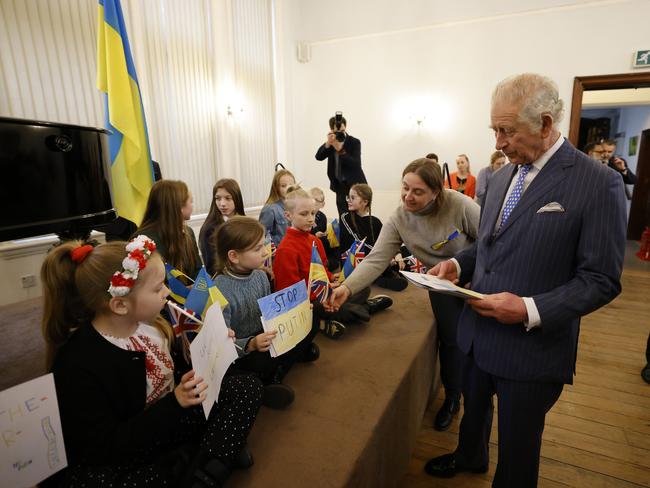A young girl gives Prince Charles a “stop Putin” flag. Picture: Getty Images