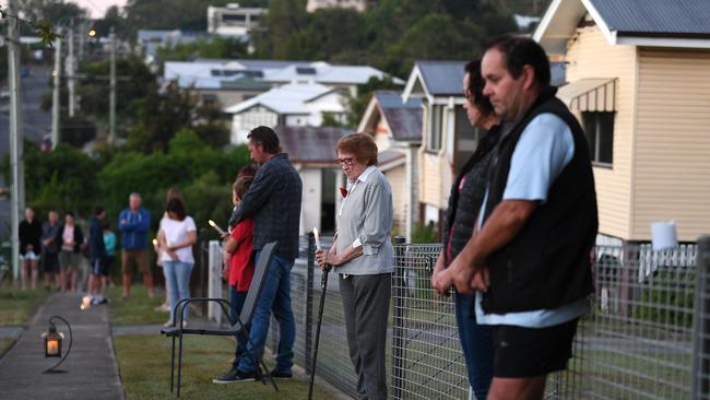 90 year-old Kathleen Callaghan (centre) and her neighbours stand outside their homes at dawn to commemorate Anzac Day in Brisbane, Saturday, April 25, 2019. Anzac Day is a national day of remembrance to commemorate the service and sacrifice of Australian and New Zealand service men and women. Due to COVID-19 restrictions marches and commemorative services have been banned for the first time in more than a century. (AAP Image/Dan Peled) NO ARCHIVING
