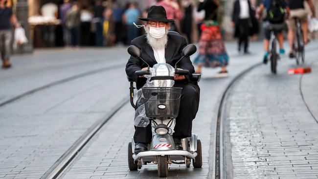 An elderly man navigates a busy street on a three-wheeled mobility scooter along a street in Jerusalem. Picture: AFP