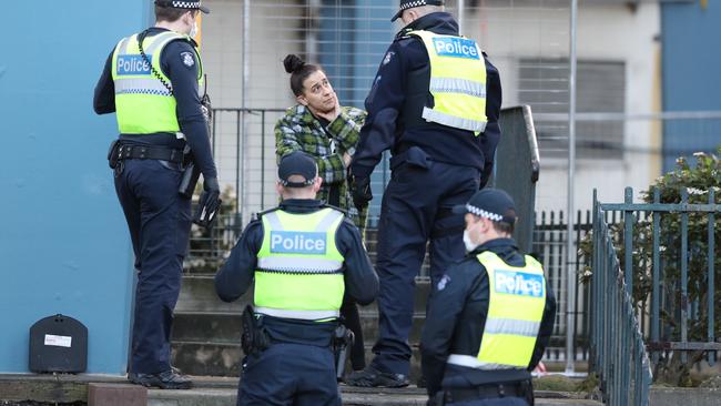 Police speak to a woman outside the Racecourse Rd buildings in Flemington which have been locked down by the Victorian Government in an attempt to stop the outbreak of COVID-19. Picture: David Crosling