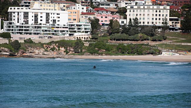 A lone surfer ignores closed beach signs to go for a surf at Bondi Beach on Sunday.