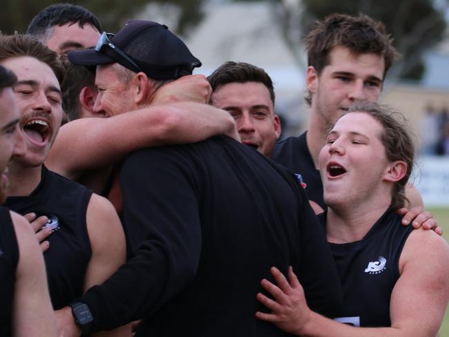 Port District players celebrate with coach Simon Maddern after the Magpies one-point win over Unley Mercedes. Picture: Kym Stegmeyer