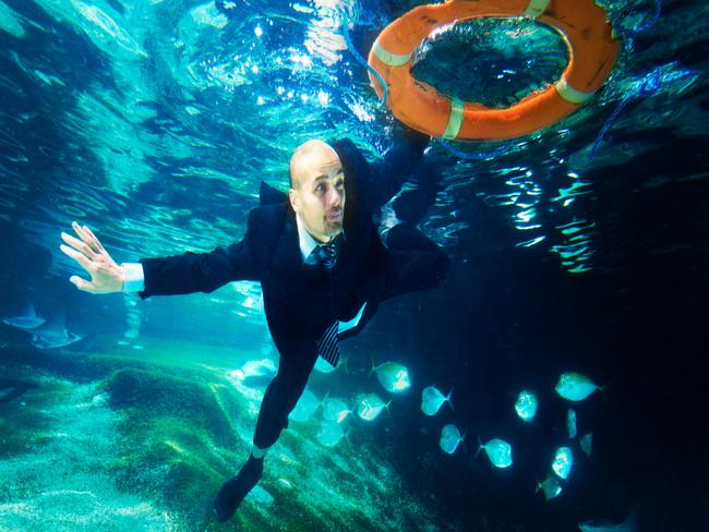 Business man swiming under water holding on to a lifebuoy