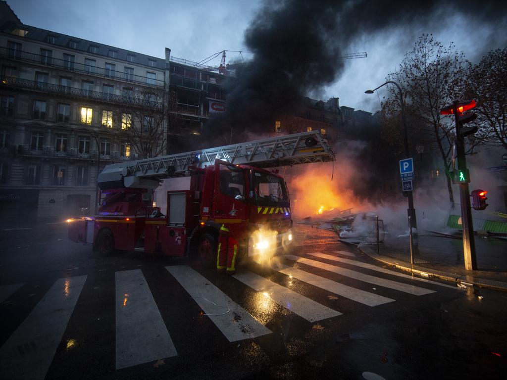 Firefighters work to put out cars set on fire on a road nearby Arc de Triomphe. Picture: Getty