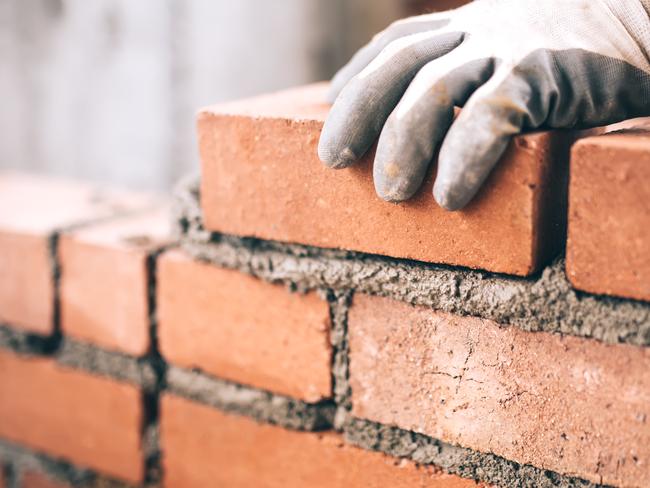 Close up of industrial bricklayer installing bricks on construction site