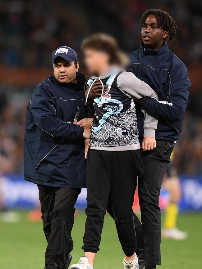 A pitch invader is escorted off Adelaide Oval by security during the round three Showdown between Port Adelaide. Picture: Mark Brake / Getty Images