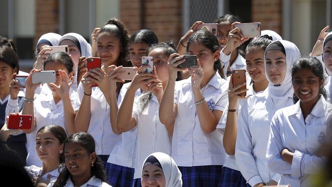 Excited schoolgirls gret Harry and Meghan with their mobile phones. Picture: AP