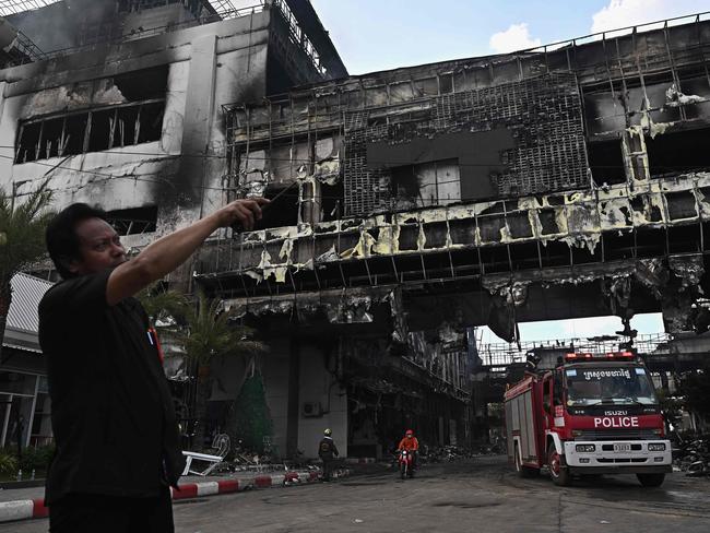 A man points next to a destroyed part of the Grand Diamond City hotel-casino following a major fire in Poipet on December 29, 2022. Picture: Lillian Suwanrumpha / AFP.