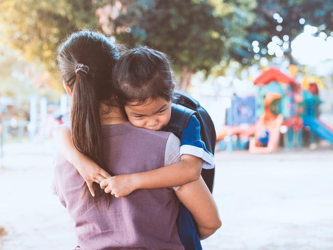 Back to school. Cute asian pupil girl with backpack hugging her mother with sadness in the playground before go to classroom in the school.