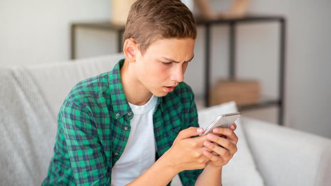 Angry teenager looking at smartphone screen, home interior, copy space  istock image