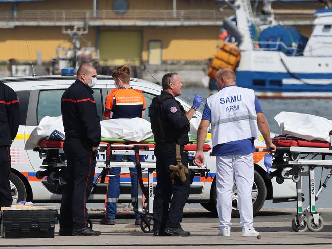 TOPSHOT - Firefighters, a police officer and a doctor of the SAMU emergency unit stand next to bags containing the bodies of migrants who died after the sinking of a migrant boat attempting to cross the English Channel to England, in Boulogne-sur-Mer, northern France, on September 3, 2024. Twelve migrants died off the northern French coast on September 3 trying to cross the Channel to England, the French government said, raising an earlier death toll. Interior Minister Gerald Darmanin said on X that two migrants were still missing in the "terrible disaster" and several were injured after their boat ran into trouble, sparking a major rescue operation. (Photo by Denis Charlet / AFP)