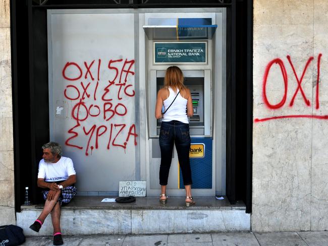 Fiscal control ... a woman withdraws money from an ATM with the words ‘No to fear‘ freshly graffitied on the wall. Picture: AFP/Sakis Mitrolidis