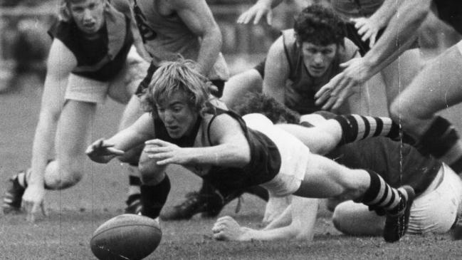 Footballer Kym Hodgeman dives on the ball. Glenelg vs Sturt Grand Final match at Football Park 28 Sep 1974.