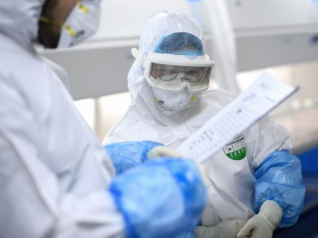 This photo taken on February 6, 2020 shows a laboratory technician talking with each other as they work on samples from people to be tested for the new coronavirus at "Fire Eye" laboratory in Wuhan in China's central Hubei province. - BGI Group, a genome sequencing company based in southern China, said it opened on February 5 a lab in Wuhan able to test up to 10,000 people per day for the virus. The official Chinese death toll from the coronavirus outbreak rose on February 7 to 636, with the government saying total infections had climbed past 30,000. (Photo by STR / AFP) / China OUT