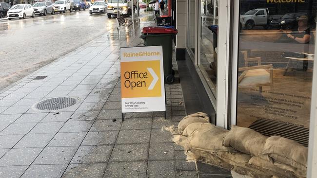 Overflowing stormwater drains on Pittwater Rd, Dee Why, on Tuesday forced the Raine &amp; Horne office to stack sandbags at its front door – just in case. Picture: Jim O'Rourke