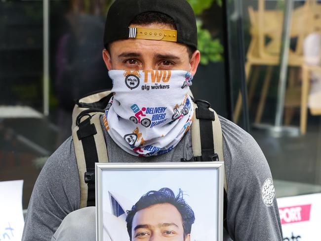 SYDNEY, AUSTRALIA - NewsWire Photos NOVEMBER 25, 2020: A delivery rider poses for a photo with a picture of one of the Delivery riders who didn't come home after work, in the Sydney CBD as Delivery riders and union workers gather in their honour to express their rights for safety at work in Sydney, Australia. Picture: NCA NewsWire / Gaye Gerard