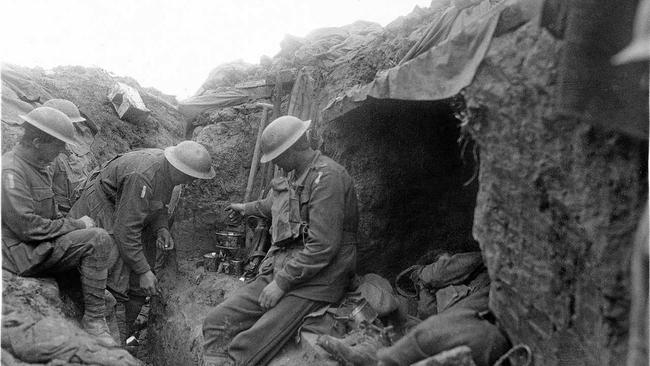 Three soldiers warm a mess tin of tea over a candle in the reserve line during the fighting near Bullecourt. Picture: Australian War Memorial (E00456)